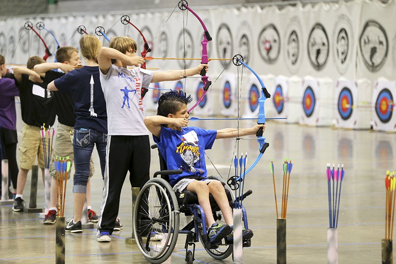 Mobility-impaired archer competing alongside other youths.