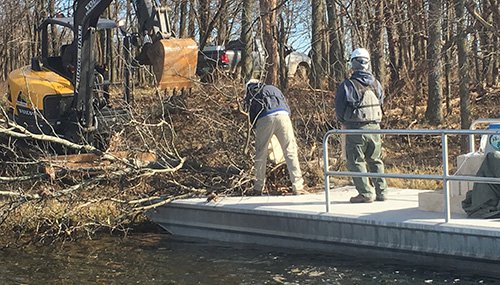 Excavator moving trees to AGFC barge