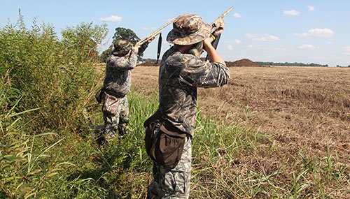 Two dove hunters standing in the field shooting