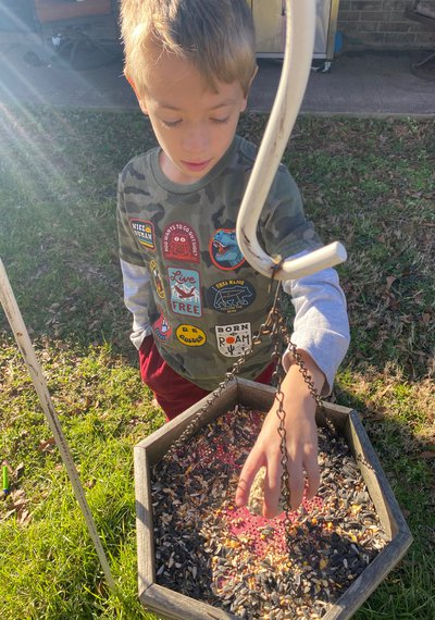 Young boy helping fill a bird feeder