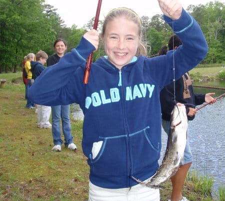 Young girl holding her catch at fishing derby