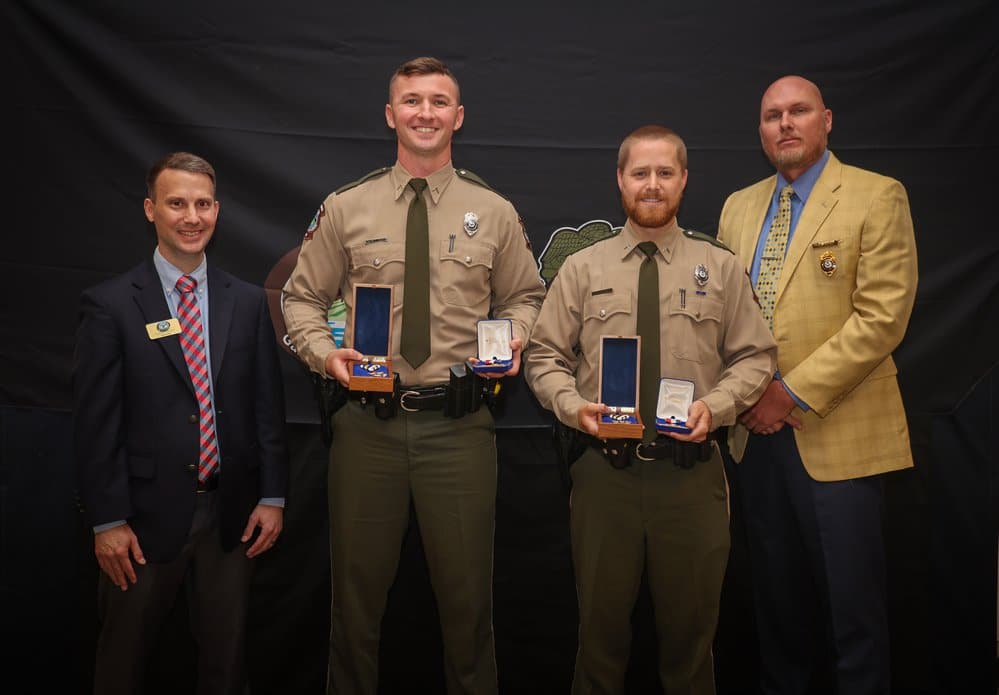 AGFC Chief of Staff (left) and AGFC Lt. Col. Jake Dunn (far right) presented the Warden's Star and Lifesaving Medal to Game Warden First Class Channing Sanders (left) and Cpl. Bradley Huggins (right). Cpl. Tyler Webb (not pictured) also received a lifesav
