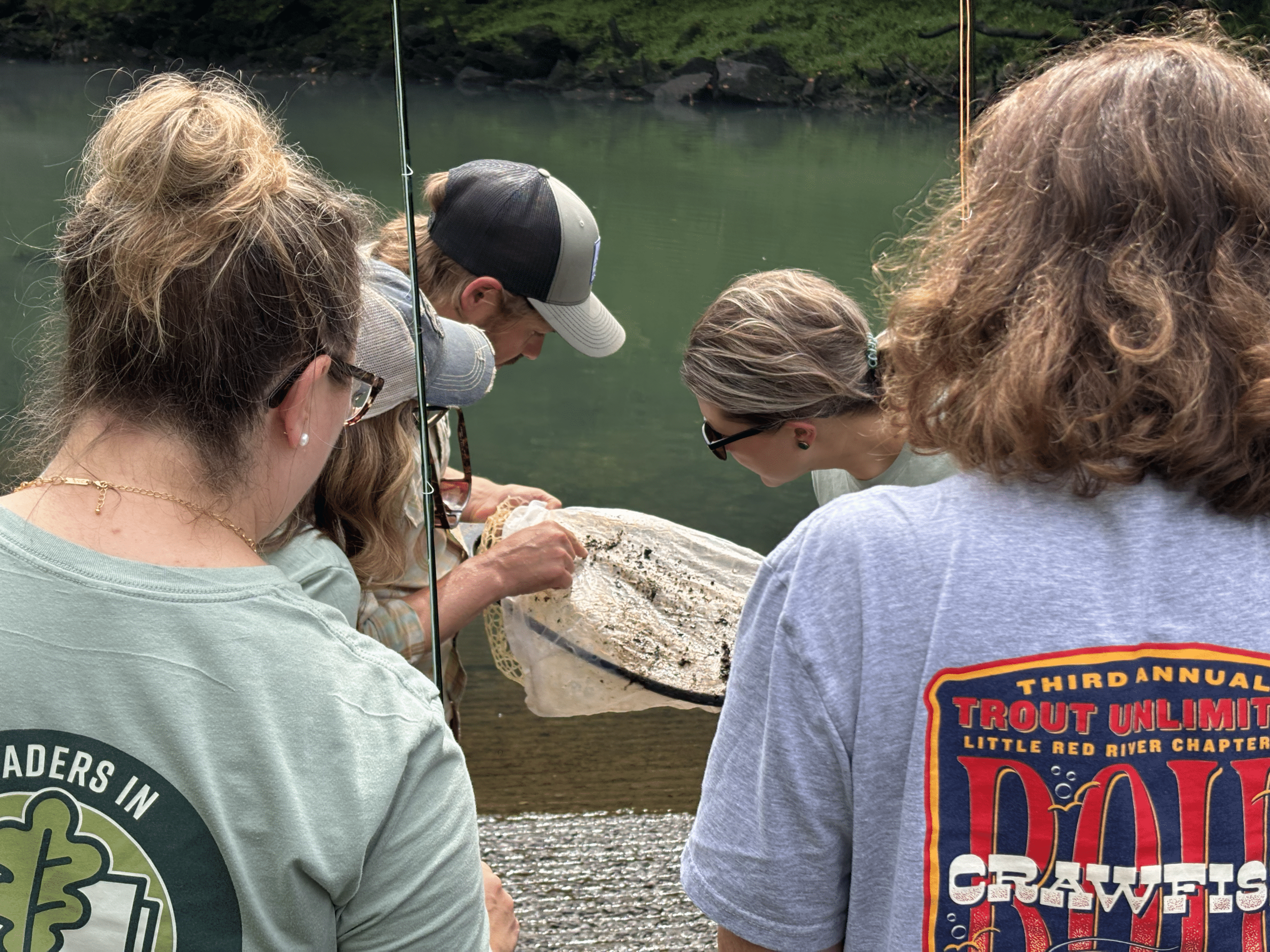 Teachers looking at a net gathered from water. A teacher is explaining what is on the net.