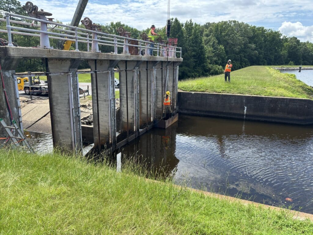 Water control structure on Mike Knoedl Tri-County Lake, with construction workers examining the structure.