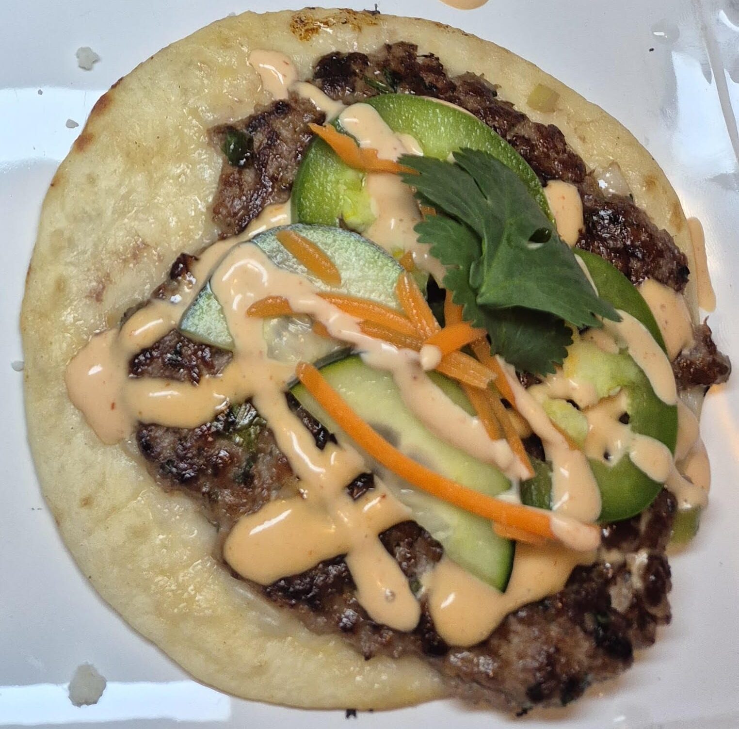 A venison-based bahn mi smash taco with sauce and seasonings.