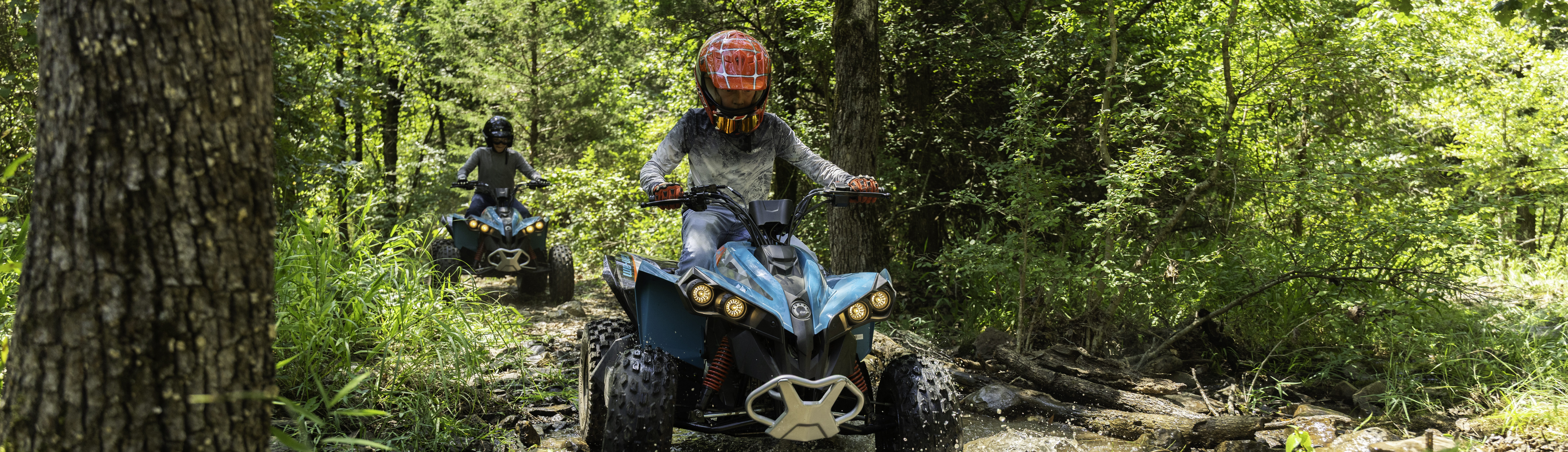 Two children driving ATVs.